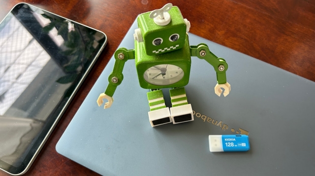 緑色のロボットの置き時計とUSBメモリーと新しいPC